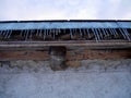 Low angle view of icicles hanging from roof of old rustic barn. Royalty Free Stock Photo