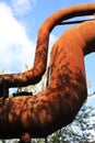 Landschaftspark Duisburg, Germany: Low angle view on isolated curved corroded pipeline against blue sky and trees