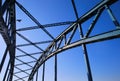 Low angle view on isolated symmetrical industrial steel bridge deck against blue sky with cross struts and metal beams focus on