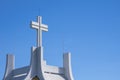 Low angle view of large cross on rooftop of white church against blue sky background Royalty Free Stock Photo