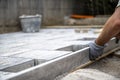 Male hands measuring and leveling sand and cement tiles for precise pavement of the outside patio