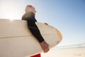 Low angle view of man carrying surboard while standing at beach Royalty Free Stock Photo
