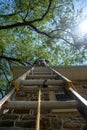 Low angle view of man on a ladder cleaning gutters of a stone house vertical image Royalty Free Stock Photo