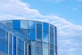 Glass office building in modern style against white clouds in blue sky background Royalty Free Stock Photo