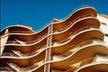 Low angle view of a modern building with balconies under sunlight and a blue sky Royalty Free Stock Photo