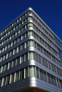 Low angle view on modern building with silver shiny reflecting facade against deep blue cloudless sky