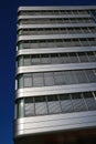 Low angle view on modern building with silver shiny reflecting facade against deep blue cloudless sky Royalty Free Stock Photo