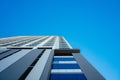 Low-angle view of a modern skyscraper rising against the blue sky