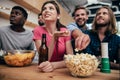 low angle view of multiethnic group of friends watching football match at bar with chips popcorn fan horn and beer Royalty Free Stock Photo