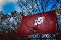 Low angle view of an old basketball hoop in a park with trees Royalty Free Stock Photo