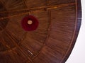 Low angle view of a parasol with red lamp in straw wicker pattern of lines and bright sky