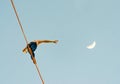 Low angle view of a person walking on a tightrope with the half moon in the blue sky