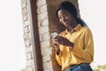 Low angle view photo of charming dark skin woman stand near window break use phone wear yellow shirt indoors in office