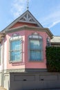 Low angle view of pink eclectic-style patrimonial stucco house with large bay windows seen against blue sky