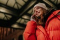 Low-angle view portrait of charming young woman in warm winter hat and jacket talking using holding mobile phone Royalty Free Stock Photo