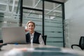 Low-angle view portrait of middle-aged 50s businesswoman sitting at modern office desk working on laptop do freelance Royalty Free Stock Photo