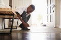 Low angle view pre-teen black boy tying his shoes before leaving home, selective focus Royalty Free Stock Photo