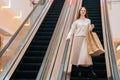 Low-angle view of pretty happy young woman holding on escalator handrail and riding escalator going down in shopping Royalty Free Stock Photo