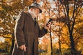 Low angle view profile photo of retired cheerful white hair grandpa walk desert park stick chatting telephone family
