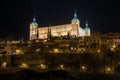 Low angle view of the Real Alcazar of Toledo, Spain (military museum) illuminated at night above the houses Royalty Free Stock Photo