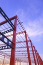 Low angle view of red and black metal castellated beam of large industrial building structure in construction site at sunset