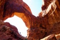 Low angle view on red sandstone bridge with people on ridge against blue sky - Double Arch, Arches National Park, Utah Royalty Free Stock Photo