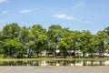 A low angle view, reflections of water, rows of trees on slate stone ground near buildings