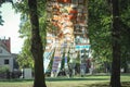 Low angle view of residential yellow brick building reflection in mirror design art object in city square greenery and Royalty Free Stock Photo