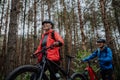 Low angle view of senior couple bikers walking and pushing e-bikes outdoors in forest in autumn day.