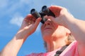 Low angle view of a senior woman with binoculars outdoors, birdwatching Royalty Free Stock Photo
