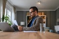 Low angle view of serious young businessman dressed in suit reading document while working at desk Royalty Free Stock Photo