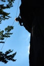 Low angle view silhouette of a girl in safety harness climbing up the rock against blue sky Royalty Free Stock Photo