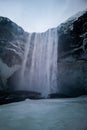 Low angle view on sixty meter tall Skogafoss waterfall in Iceland. Water pouring over icy cliffs in remote Nordic winter landscape Royalty Free Stock Photo