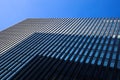 Low angle view on skyscraper facade with different symmetrical shades and monochrome geometrical windows pattern against deep blue