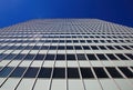 Low angle view on skyscraper facade with geometric symmetrical pattern lines against deep blue cloudless sky