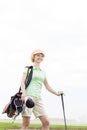 Low angle view of smiling female golfer standing against clear sky