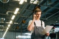 Low-angle view of smiling handsome young mechanic male wearing uniform holding clipboard and talking on mobile phone. Royalty Free Stock Photo