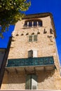 Low angle view on stone facade of typical French house and balcony with ancient ornate lattice work against blue sky and green Royalty Free Stock Photo