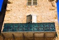 Low angle view on stone facade of typical French house and balcony with ancient ornate lattice work - Castellane, France