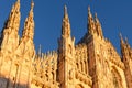 Sunlit front facade of Duomo di Milano at dusk