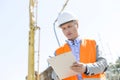 Low angle view of supervisor writing on clipboard at construction site Royalty Free Stock Photo