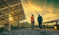 Low angle view of technician walks with investor through field of solar panels, Alternative energy to conserve the world`s energy