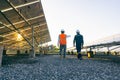 Low angle view of technician walks with investor through field of solar panels, Alternative energy to conserve the world`s energy