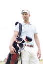 Low angle view of thoughtful mid-adult man carrying golf club bag against clear sky Royalty Free Stock Photo