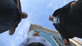 Low angle view of three business men standing outdoor near office and talking. Businessmen meet and speaking outside in