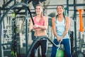 Two beautiful and strong women waving battle ropes during functional training