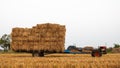 Low-angle view of a walk-behind tractor carrying piles of straw bales Royalty Free Stock Photo