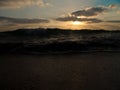 Low angle view of a wave splashing on shore under a cloudy sky at sunset