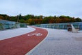 Low-angle view of winding red color bike lane with white bicycle sign on the New Pedestrian Bridge in Kyiv, Ukraine Royalty Free Stock Photo