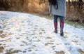 Low angle view of woman walking on snow covered trail in woods a Royalty Free Stock Photo